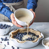 Pouring batter from Pantry Bowl over blueberries