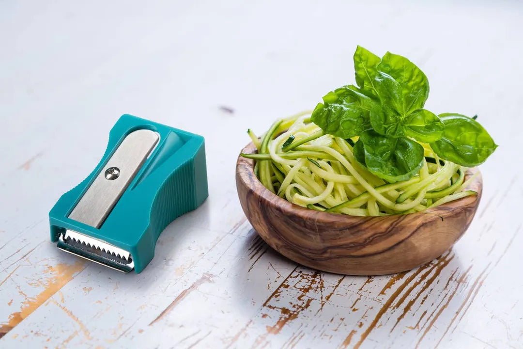 Teal Karoto Julienne beside a wooden bowl of thin zucchini strips topped with basil