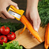 Using the straight peeling blade of a yellow Karoto to peel a carrot over a wooden cutting board
