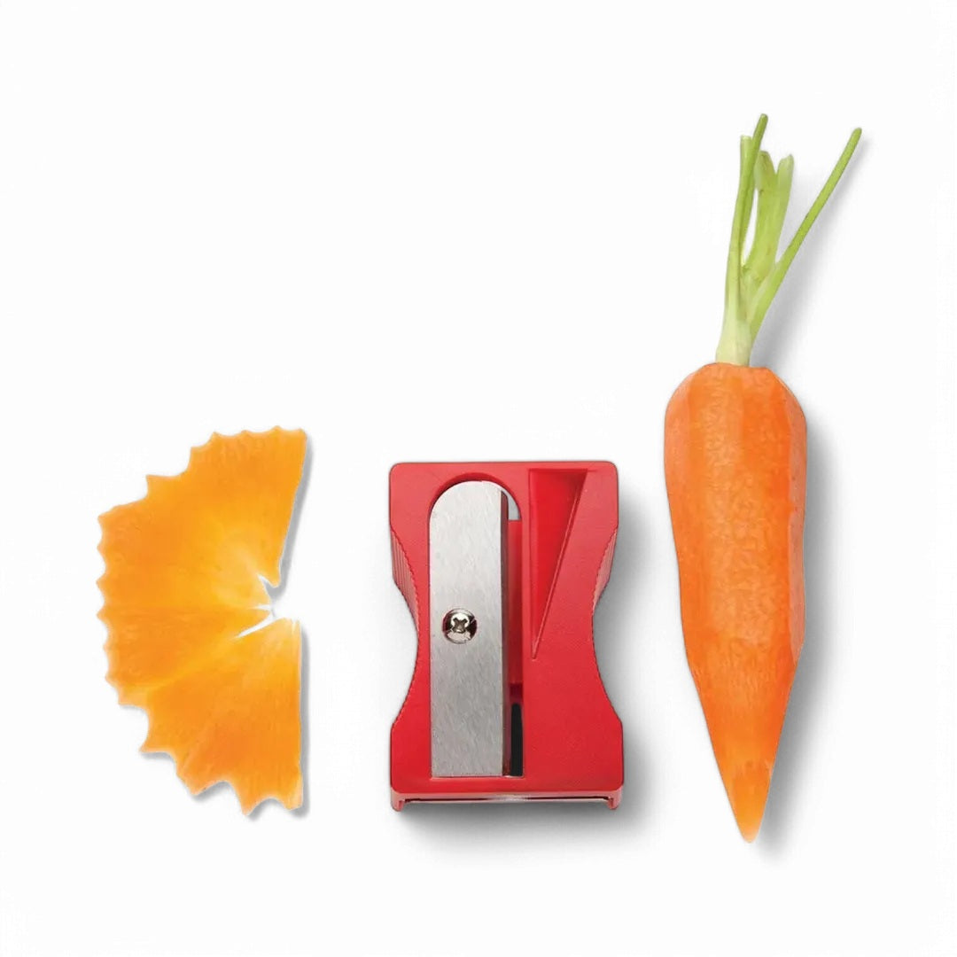 Red Monkey Business Karoto vegetable peeler and curler beside a carrot and curled carrot ribbon